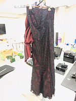 Full view of floor-length black lace over burgundy gown hanging