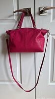 Front view of Coach hot pink pebbled leather bag with shoulder strap attached