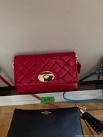 Front view of red quilted Coach bag on shelf