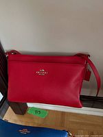 Front view of red Coach pebbled leather crossbody bag showing overall condition