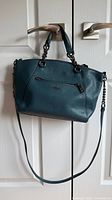 Front view of Coach teal pebble leather satchel with chain handles and crossbody strap