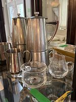 Stainless espresso maker, frothing pitcher, two glass creamers grouped together