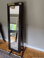 Front view of dark brown cheval mirror armoire on stand