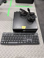 Desktop tower, webcam, power cable coiled on top, keyboard in front