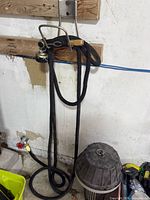 Hose hanging on wall with brass fittings and black metal nozzle