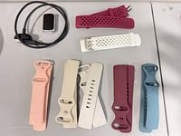 All items—tracker module, charger and eight bands laid out