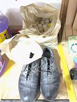 Top view of pair of FootJoy black golf shoes and bag of golf balls
