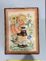 front view of porcelain wall plaque showing boy, flowers, bird