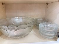 Large scalloped serving bowl and stack of small bowls in cabinet