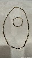 Necklace and bracelet laid flat showing full lengths and matching design