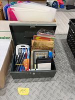 Open metal lock box showing pens and greeting cards
