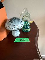 Mushroom and abstract glass paperweights on shelf