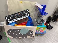 Overall lot showing keyboard inside elephant storage bin, launcher, board games, tub