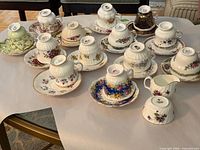 Multiple teacup and saucer pairs and creamer laid out