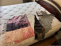 Five scarves and shawls laid out on bed showing colors and styles
