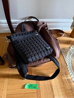 Black Lug quilted crossbody resting on brown convertible backpack