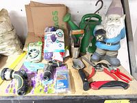 Shelf overview showing gnome, watering can, hand tools, hose nozzles, gloves and plant ties