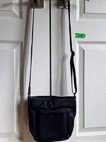 Full view of navy nylon Lululemon crossbody bag hanging by strap