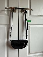 Full view of black nylon Lululemon crossbody/fanny pack hanging, shows size and design