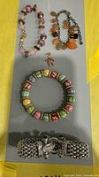 Overview of four bracelets and one charm on display board