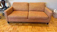 Front view of orange terracotta 2-seater sofa showing overall form and leg style