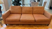 Front view of sofa showing three cushions, arms, legs, color