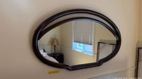 Full view of oval cherry wood framed mirror mounted on wall