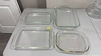 Four clear glass Pyrex baking dishes of varying sizes on table