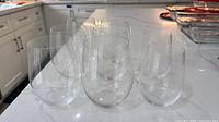Eight stemless wine glasses grouped on countertop