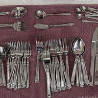Full assortment of forks, spoons, serving pieces laid out on towel