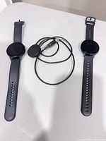 Front view of two Samsung Galaxy Watch smartwatches and charging cable