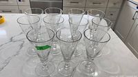Group of 11 clear glass wine glasses on countertop