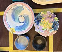 All four ceramic pieces together (swirl bowl, floral plate, blue bowl, black bowl)