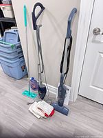 Full view of Shark steam mop, Bissell FeatherWeight vacuum, flat spray mop, microfiber pads, cleaning solution bottle