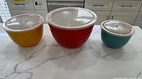 Three nested bowls with lids showing exterior colors and size comparison