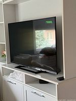 Front view of Sony 50" TV on stand with remote visible