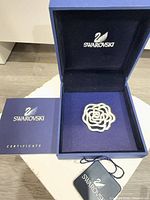 Brooch in open blue Swarovski box with certificate booklet and hang tag visible