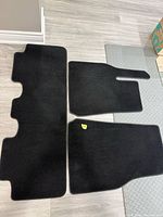 Three black carpet floor mats arranged on floor