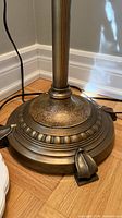 Close view of tiered antique brass base and cord