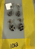 Both pairs of silver-tone crystal teardrop earrings displayed
