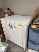 Front view of white two-door cabinet, hardware visible