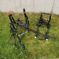 Two black metal car bike racks lying on grass