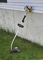 Full view of gas string trimmer leaning against wall