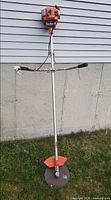 Full view of gas brush cutter showing entire length, handles, shaft, blade and guard