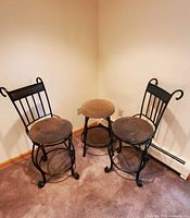 Two wrought iron swivel chairs and matching stool