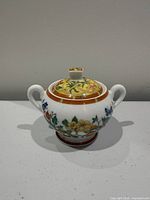 Front view of Hermès porcelain sugar bowl with lid showing floral motif and handles
