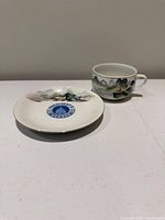 Teacup and saucer front view showing emblem and landscape art