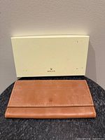 Front view of brown leather wallet with Rolex box background