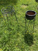 Both metal plant stands and ceramic pot in grass