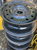 Stack of four black steel wheel rims showing side profile and general wear